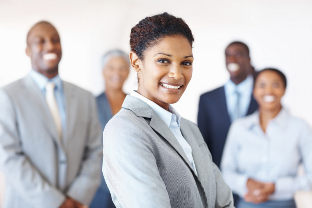 Confident woman in a suit with colleagues in the background.